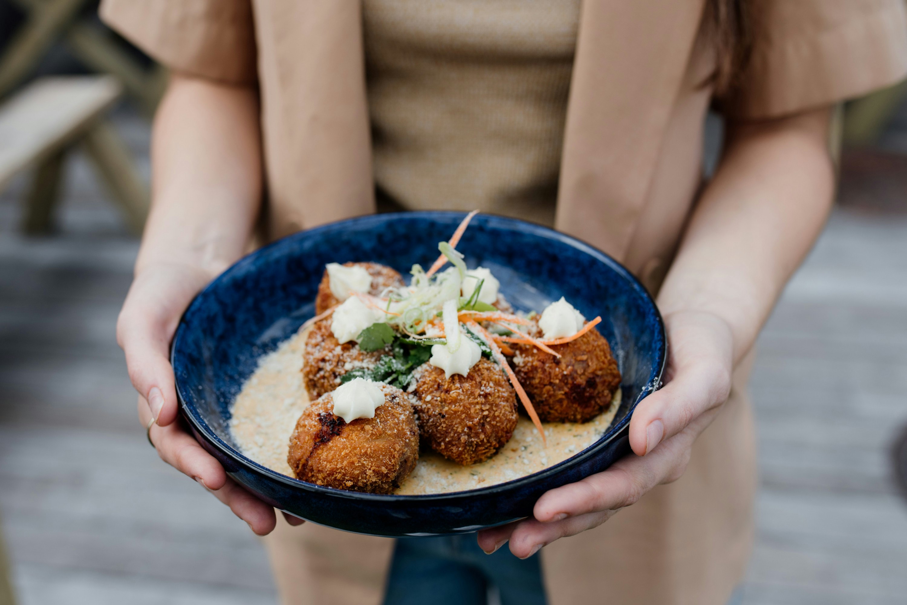 someone holding a plate of arancini balls